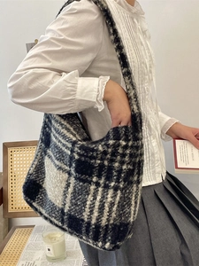 Large black and white checkered plush tote bag shown on a model in a cozy room
