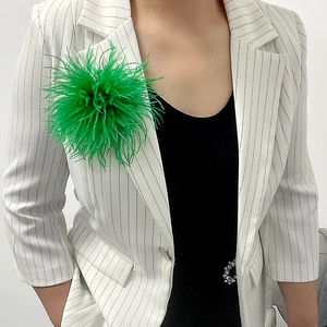 Bright green ostrich feather brooch accessory pinned on a white striped suit jacket