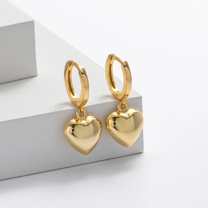 Detail of gold heart pendant earrings on a white geometric platform display