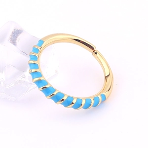 Detail of gold-plated copper ring featuring sky blue enamel spiral patterns on white background