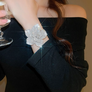 Detailed view of silver flower bracelet with crystals on wrist holding a wine glass