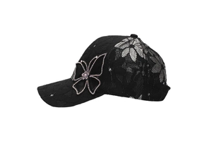 Close-up of floral lace texture and sparkling rhinestone butterfly on the black baseball cap