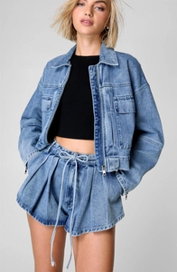 Detail of blue washed denim set featuring a cropped zip jacket and high-waist pleated shorts
