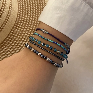 Bohemian stackable beaded bracelet set in blue and purple tones worn by a model