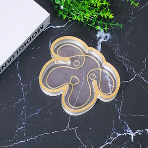 Detail view of dog-shaped resin tray with gold glitter outlines on black marble surface