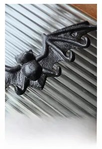 Detalle del gancho de pared de murciélago en hierro fundido con textura y agujeros de montaje
