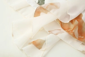 Detail of floral chiffon fabric with delicate lettuce edge and soft orange petal print