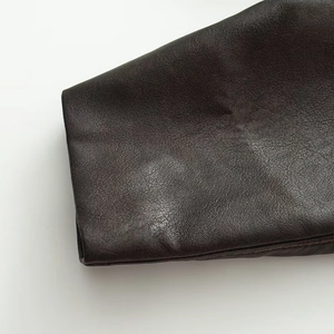 Detailed close-up showing the fine grain texture and neat stitching of dark brown faux leather