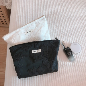 Close-up of embossed floral makeup bags in black and white with metal zippers