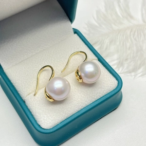 Macro shot of freshwater pearl earrings with gold hooks on a luxury jewelry box