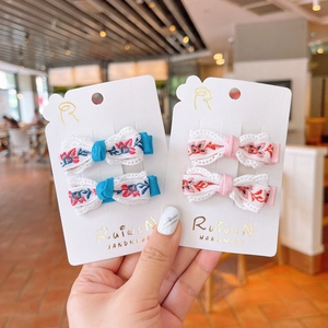 Detail of blue and pink embroidered floral bow hair clips on branded display cards
