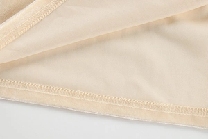 Détail de la couture surjet sur l'ourlet d'une robe en velours beige à fente latérale