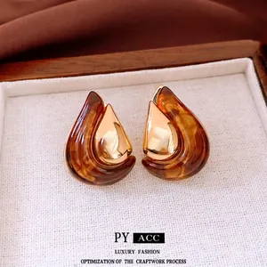 Waterdrop-shaped amber resin earrings with 18K gold-plated interior on a soft fabric display
