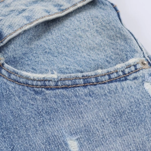 Gros plan sur la poche en denim bleu avec bords usés vintage et coutures renforcées