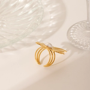 Detailed macro of a gold multi-layer ring featuring a white pearl and feather-like accents