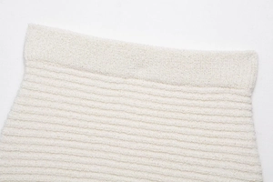 Gros plan sur la texture du tricot beige montrant les franges et le motif bouclé