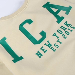Détail du col rond côtelé et de l'imprimé vert sur le sweat-shirt en coton écru