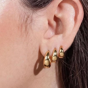 Three-piece set of golden teardrop hoop earrings in various sizes on model ear