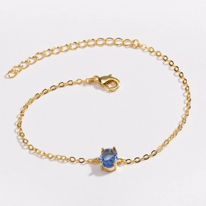 Close-up of gold-plated chain with emerald green oval zircon pendant and lobster clasp