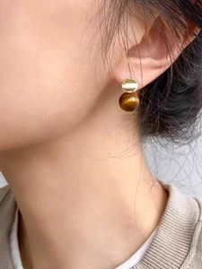 Close-up of 18k gold plated tiger eye stone drop earrings worn by a model