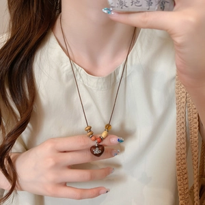 Vintage wooden bead heart pendant necklace with planetary logo on beige cotton linen shirt
