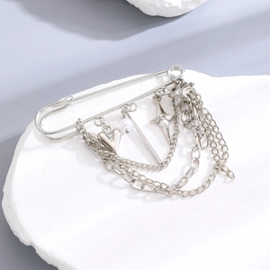Detail of silver safety pin brooch with heart, star charms and triple layer chains