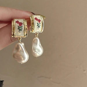 Detailed macro shot of vintage gold flower earrings with white baroque drop pearls