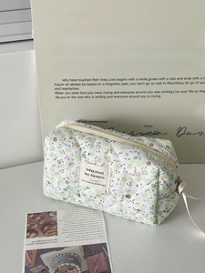 Detail of floral corduroy makeup bag with beige zipper and vintage woven label