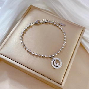 Macro view of stainless steel beaded bracelet featuring a star and moon paved pendant