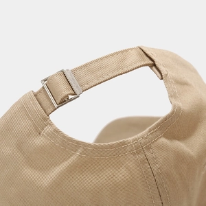 Close-up of adjustable fabric strap and smooth metal buckle on khaki baseball cap