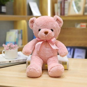 Oso de peluche rosa con un lazo a juego sentado sobre libros en un ambiente acogedor