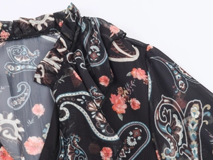 Detail of ruffle neckline and paisley floral pattern on lightweight black chiffon fabric