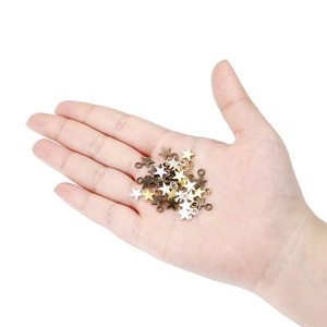 Star-shaped alloy pendants in gold and silver held by hand for DIY jewelry making
