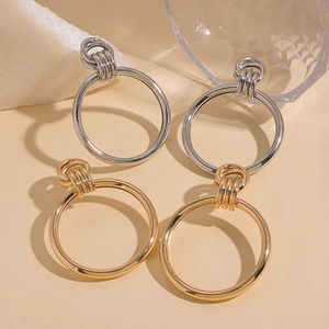 Minimalist double circle knot earrings in gold and silver finish on a beige background