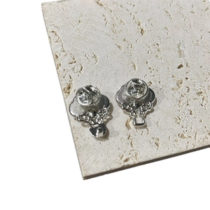 Pair of silver metal Ruyi brooches displayed on a textured stone surface from an angle