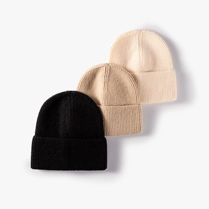 Three minimalist knit beanies in black, khaki, and cream colors on white background