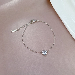 Detail of silver heart bracelet with cubic zirconia on pink satin fabric background