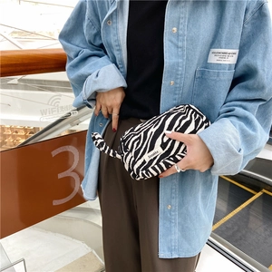 Vue détaillée d'une pochette en toile à motif zèbre tenue par une personne élégante