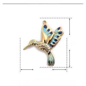 Dettaglio del ciondolo a colibrì in acciaio dorato con smalto blu e strass lucidi