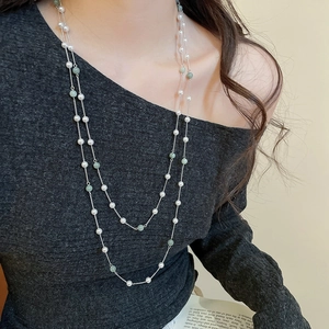 Dettaglio ravvicinato di una collana a doppio strato con perle bianche e pietre verdi