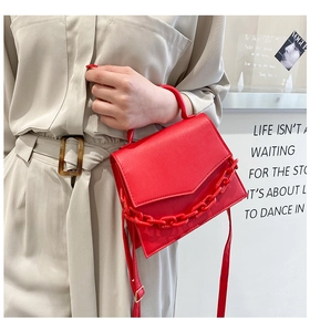 Close-up of a red leather crossbody bag with a chunky resin chain and gold hardware detail