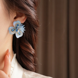 Gros plan de boucles d'oreilles fleur bleue avec pétales en cristal et perles