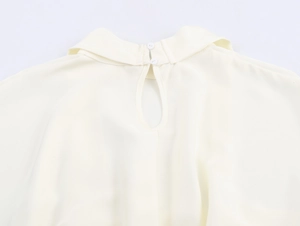 Detail van de elegante rugsluiting met witte knopen op de crème satijnen jurk