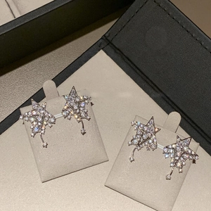 Sparkling star zircon earrings in S925 silver finish displayed on beige velvet