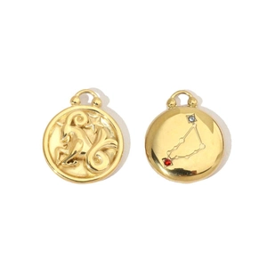 Macro detail of 14K gold plated Aries zodiac pendants with embossed ram and gem inlay