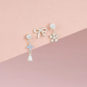 Macro detail of S925 silver moonstone stud earrings featuring blue flower and bow designs