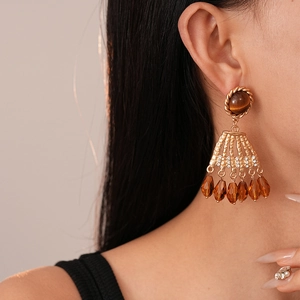 Detail of vintage gold earrings with tiger eye stone and amber crystal tassels on model