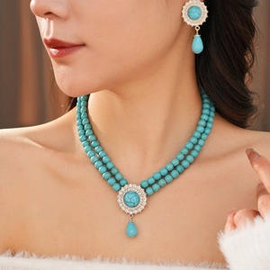 Detail of vintage double-layer turquoise pearl necklace and teardrop earring set on model
