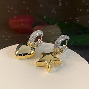 Asymmetric gold heart and star earrings with zircon inlay on polished silver hoops