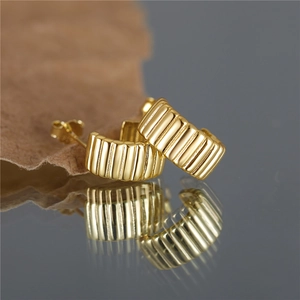 Close-up of gold star-shaped earrings with vintage pleated texture on reflective base